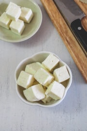 Paneer cubes in a bowl with few more cubes in back.