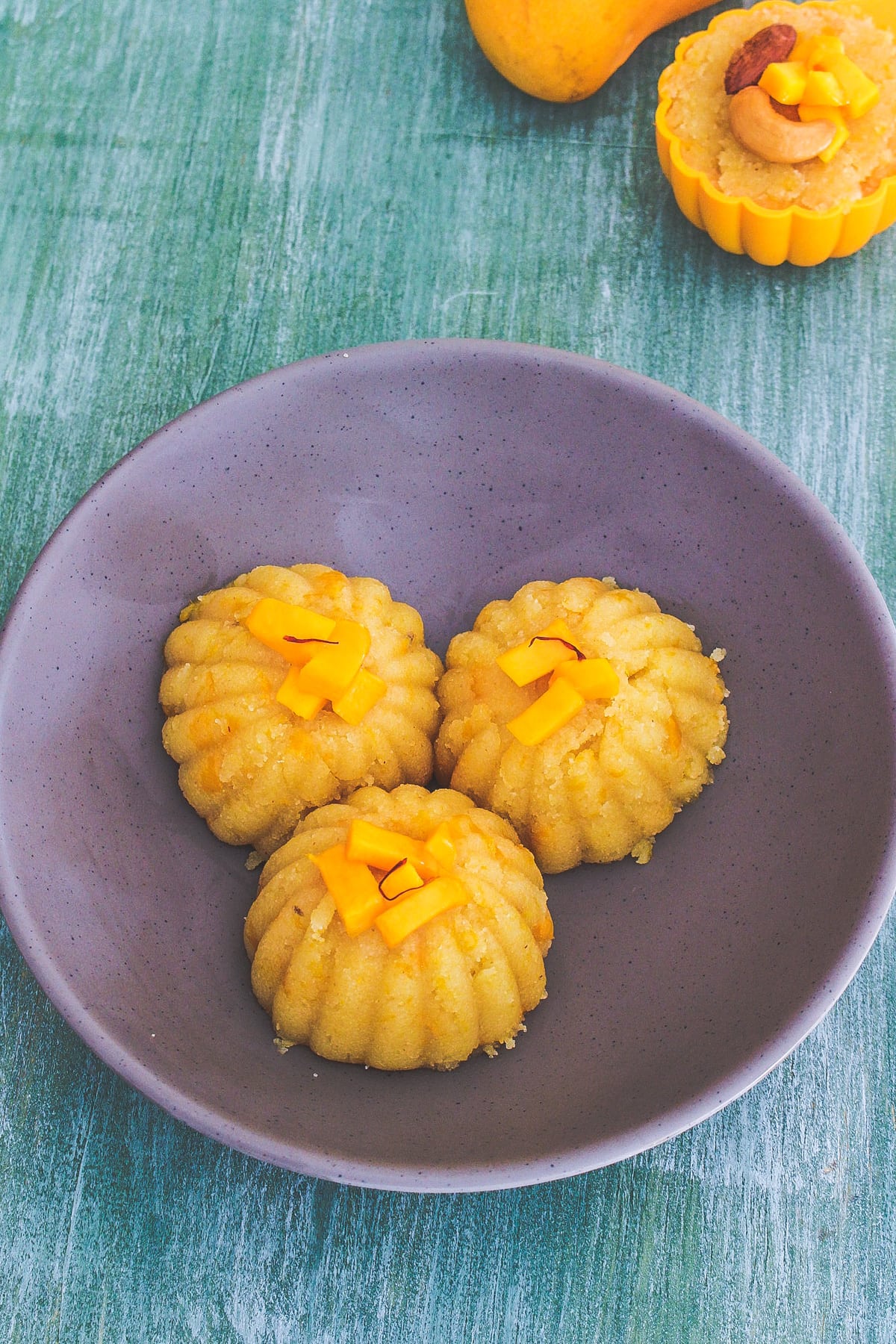 Mango halwa garnished with mango cubes and saffron stands.