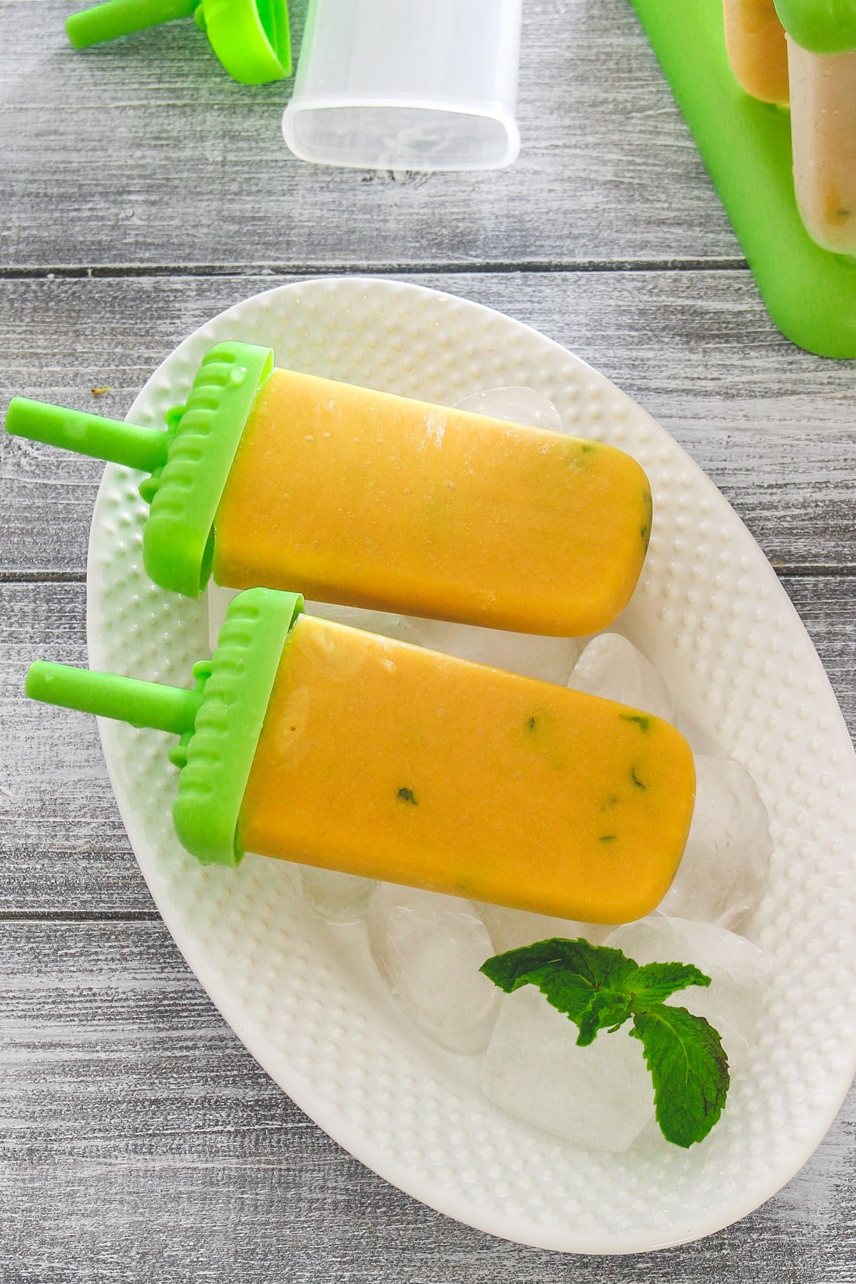 2 mango popsicles in tray of ice cubes.