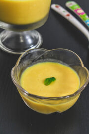 Mango pudding in a bowl garnished with mint leaf.