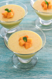 Mango pudding in individual serving cups garnished with mango cubes and mint leaves.
