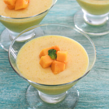 Mango pudding in individual serving cups garnished with mango cubes and mint leaves.