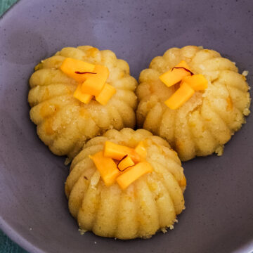 3 scoops of mango halwa garnished with mango pieces and saffron strands.