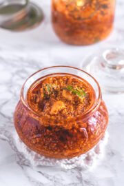 Methia keri mango pickle in a glass jar with more pickle in background.