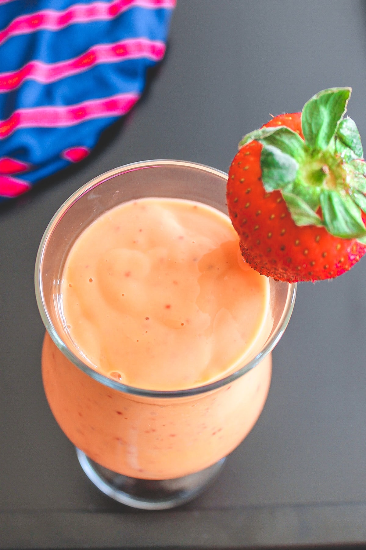 Strawberry mango smoothie in a glass garnish with a strawberry.