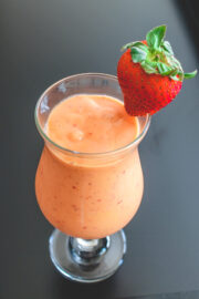 A glass of strawberry mango smoothie garnished with a whole strawberry.