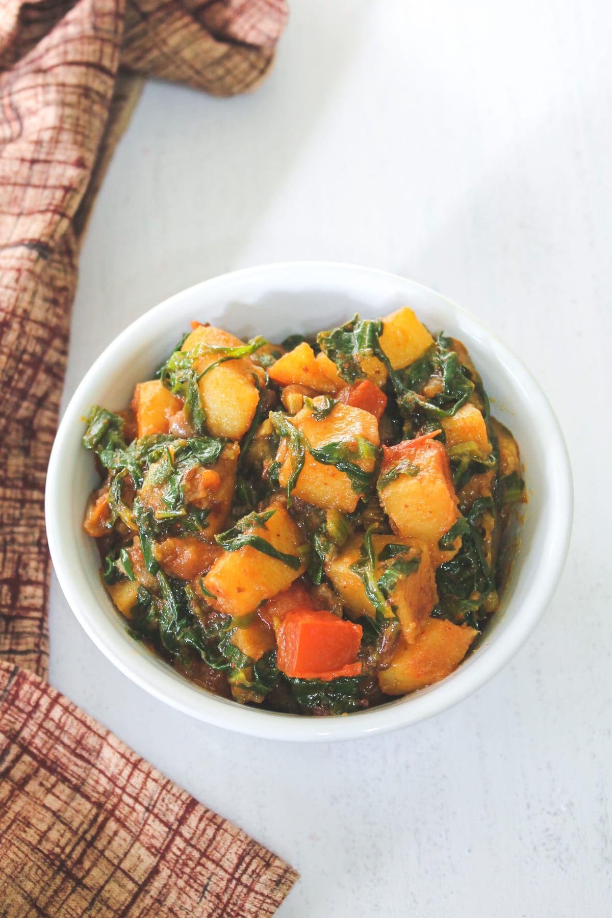 Top view of palak sabzi served in a bowl with brown napkin on the side.