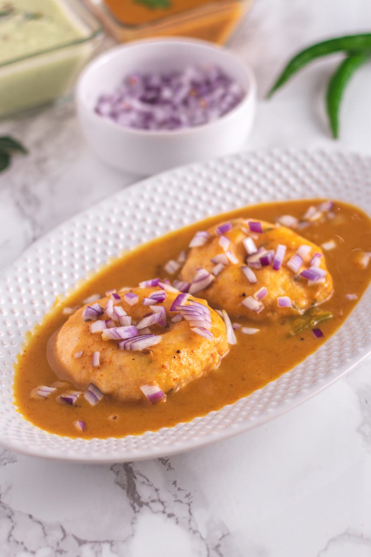 Sambar vada garnished with chopped onions.