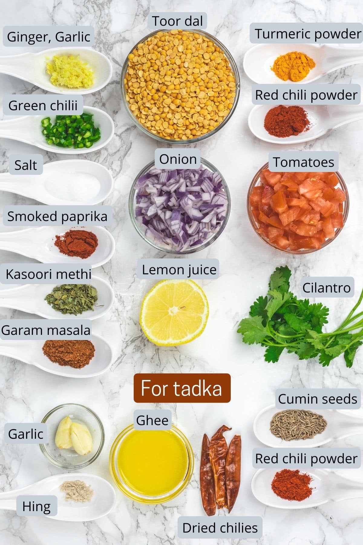 Dal tadka ingredients with labels on a marble surface.