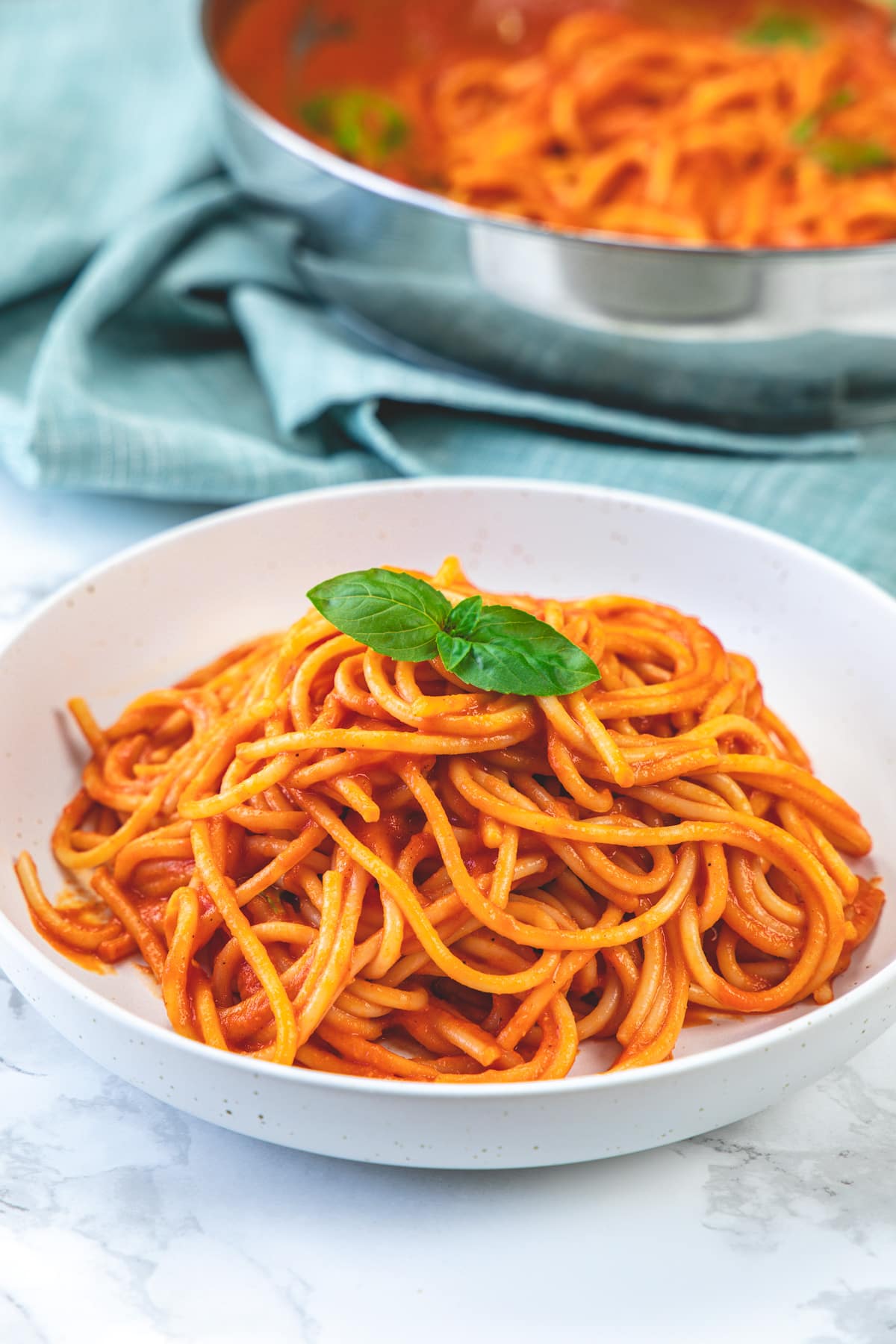 A plate of roasted red pepper pasta garnished witg basil leaves.