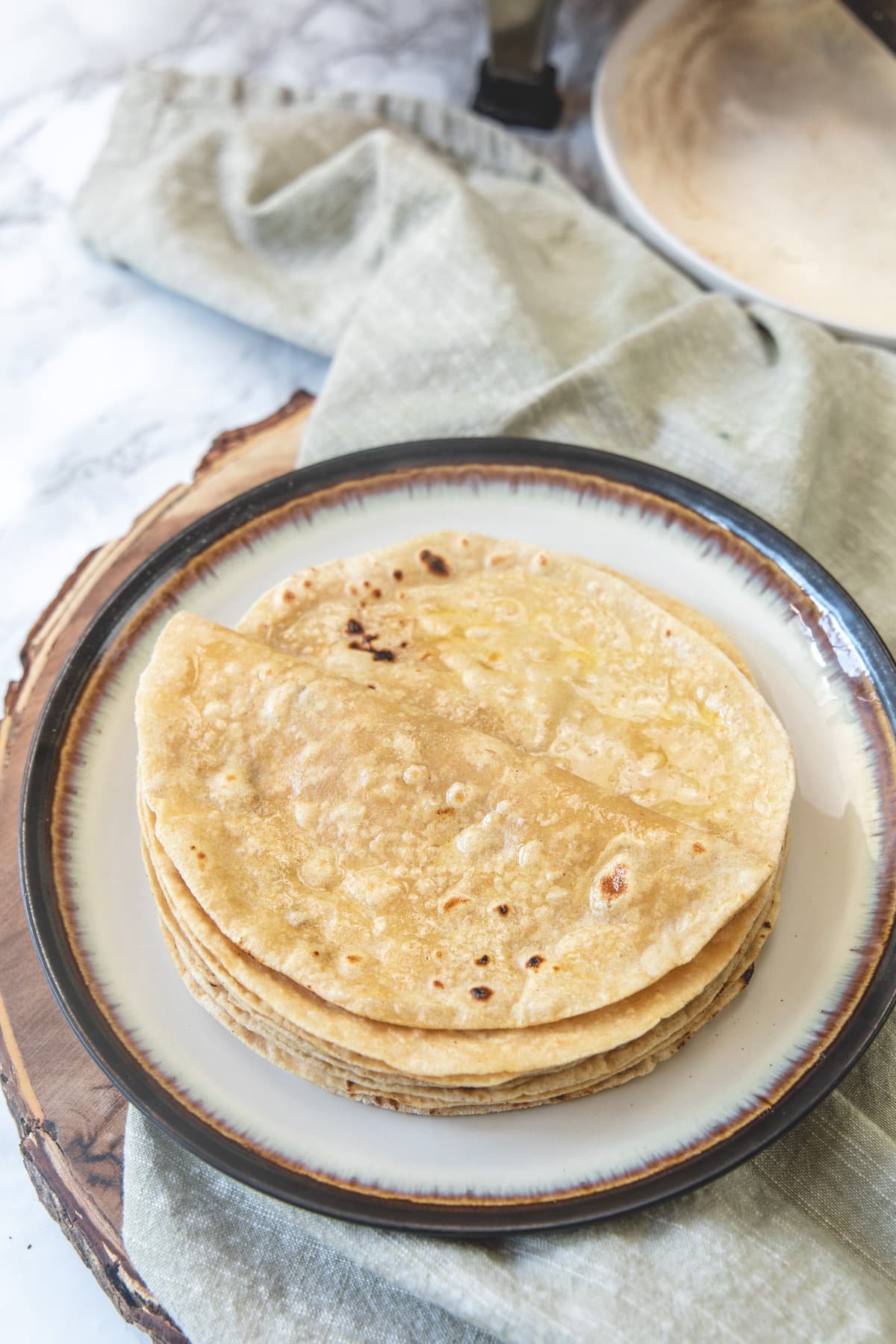 A stack of roti in a plate with napkin underneath and top roti is folded in half.