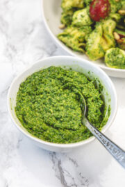 Spinach basil pesto in a bowl with a spoon inside.