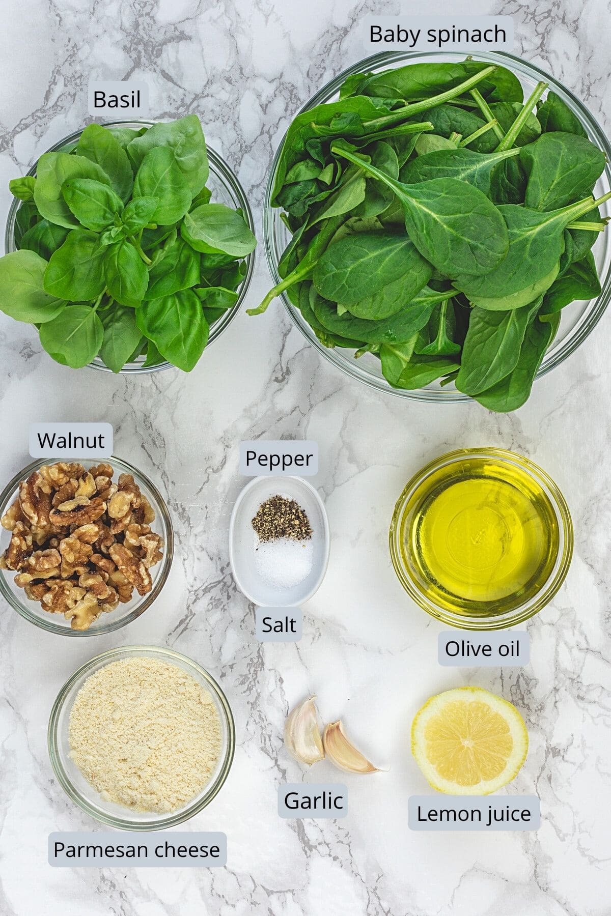 Spinach basil pesto ingredients with label on marble surface.