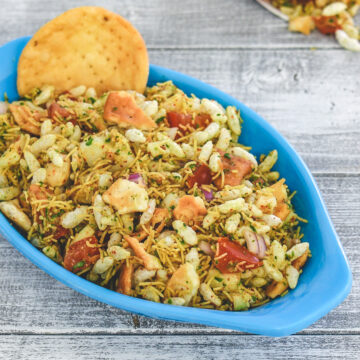 Sukha bhel with papdi on the side and more bhel in paper cone in the back.