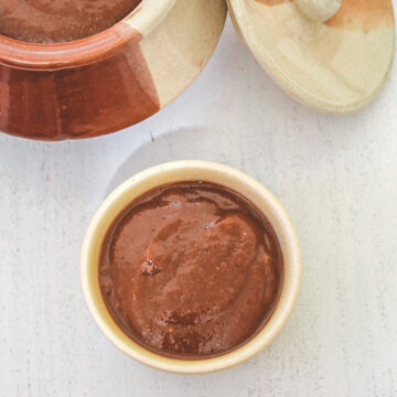 Tamarind date chutney in a small bowl with more in a bigger bowl in the back.