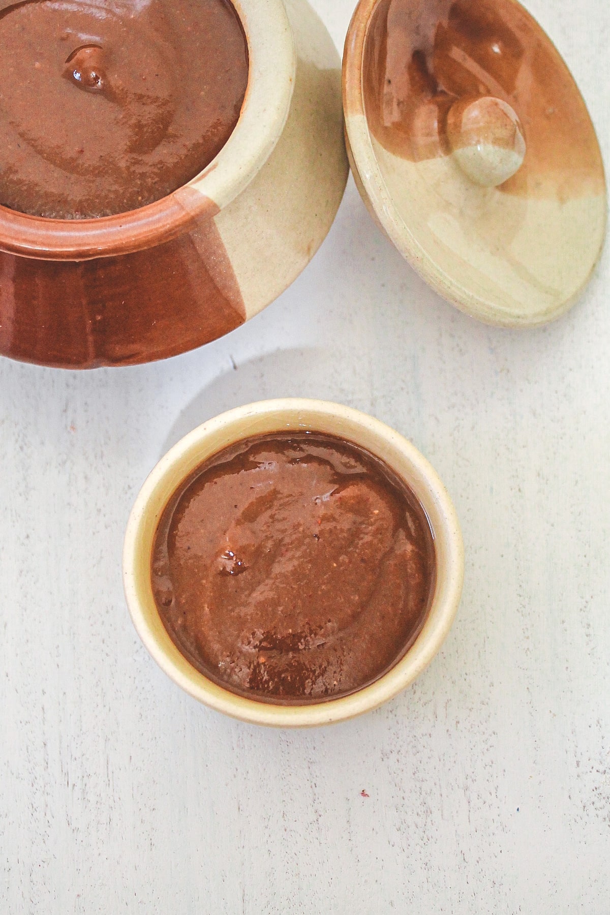 Tamarind date chutney in a small bowl with more in a bigger bowl in the back.