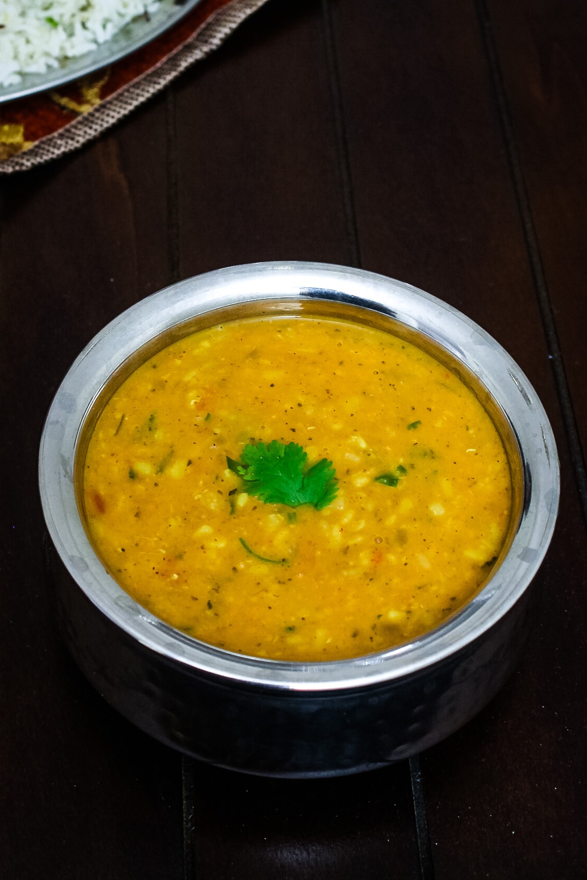 Urad dal served in steel handi and garnished with cilantro.