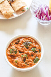 Capsicum curry served with paratha and sliced onions.