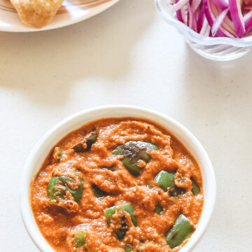 Capsicum curry served with paratha and sliced onions.