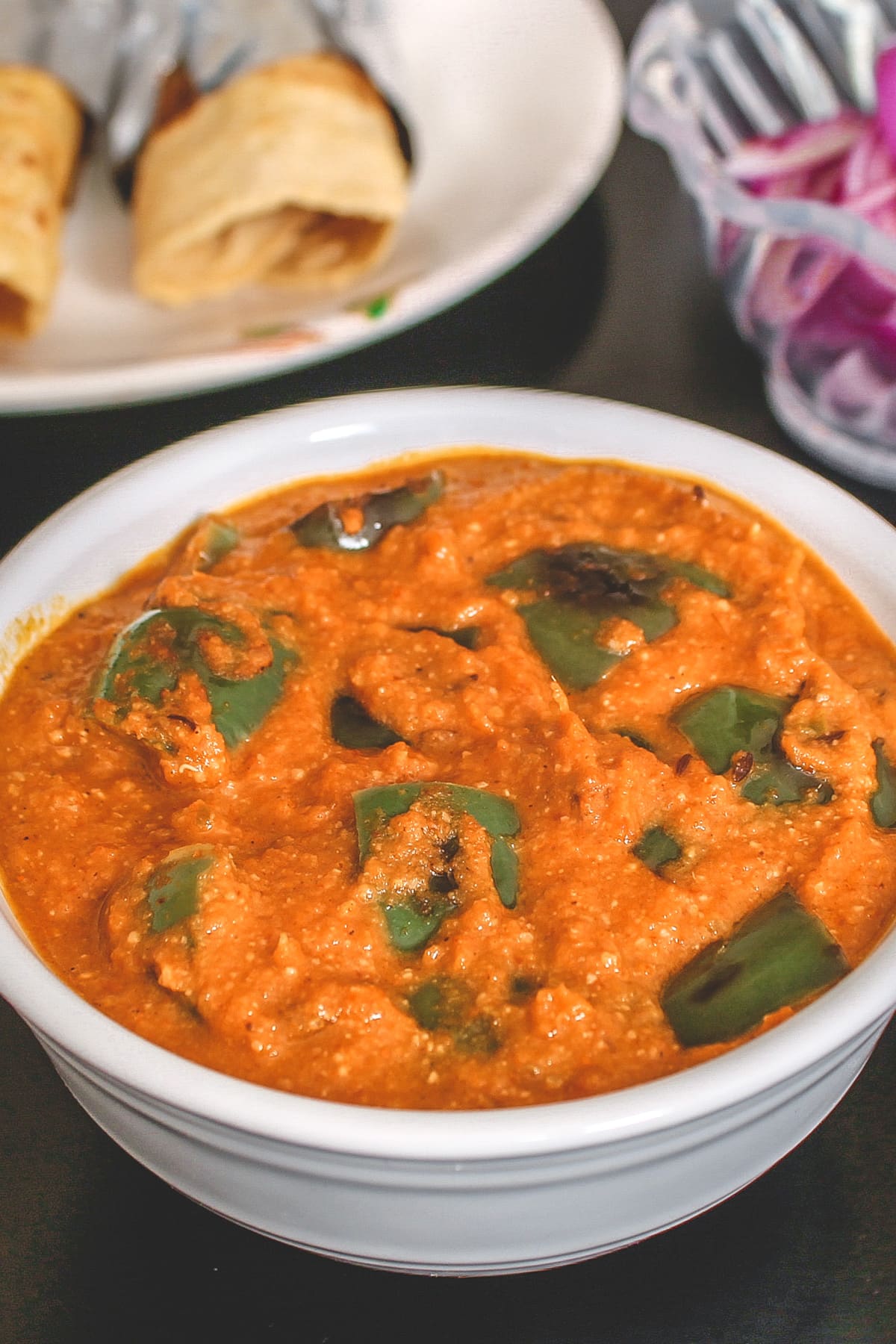 Capsicum masala curry served with 2 paratha rolled and sliced onions.