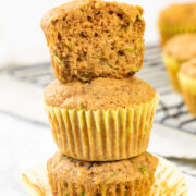 3 eggless zucchini muffins stacked with top muffin is cut into half.