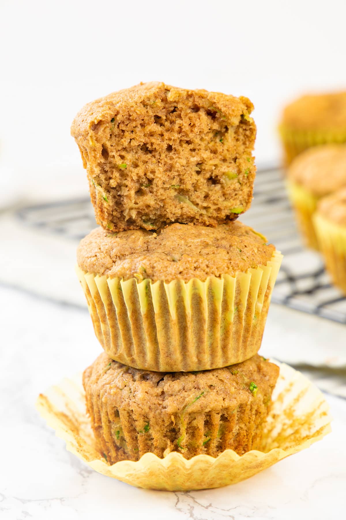 3 eggless zucchini muffins stacked with top muffin is cut into half.
