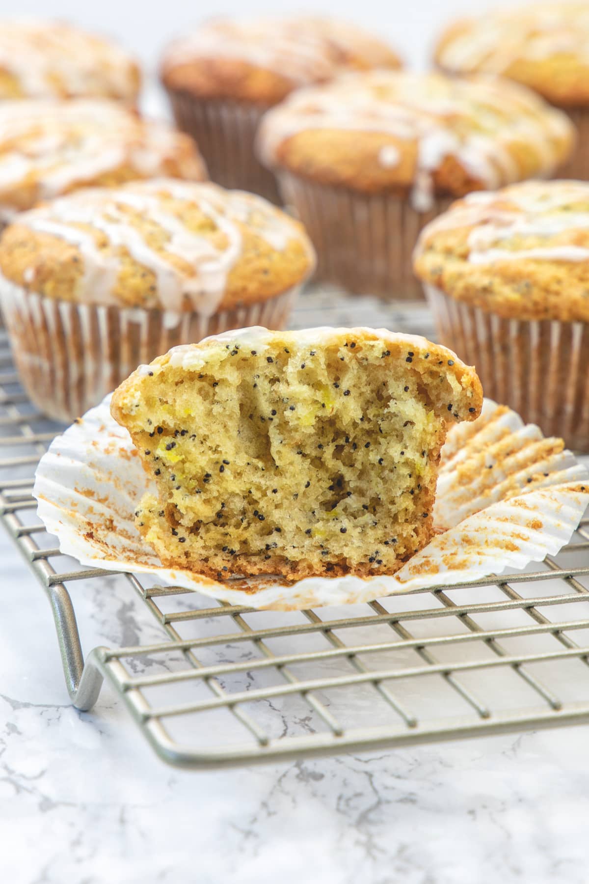 Lemon poppy seed muffin cut into half to show inside texture on a cooling rack.