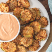 Air fried zucchini chips served with fry sauce on a wooden board.