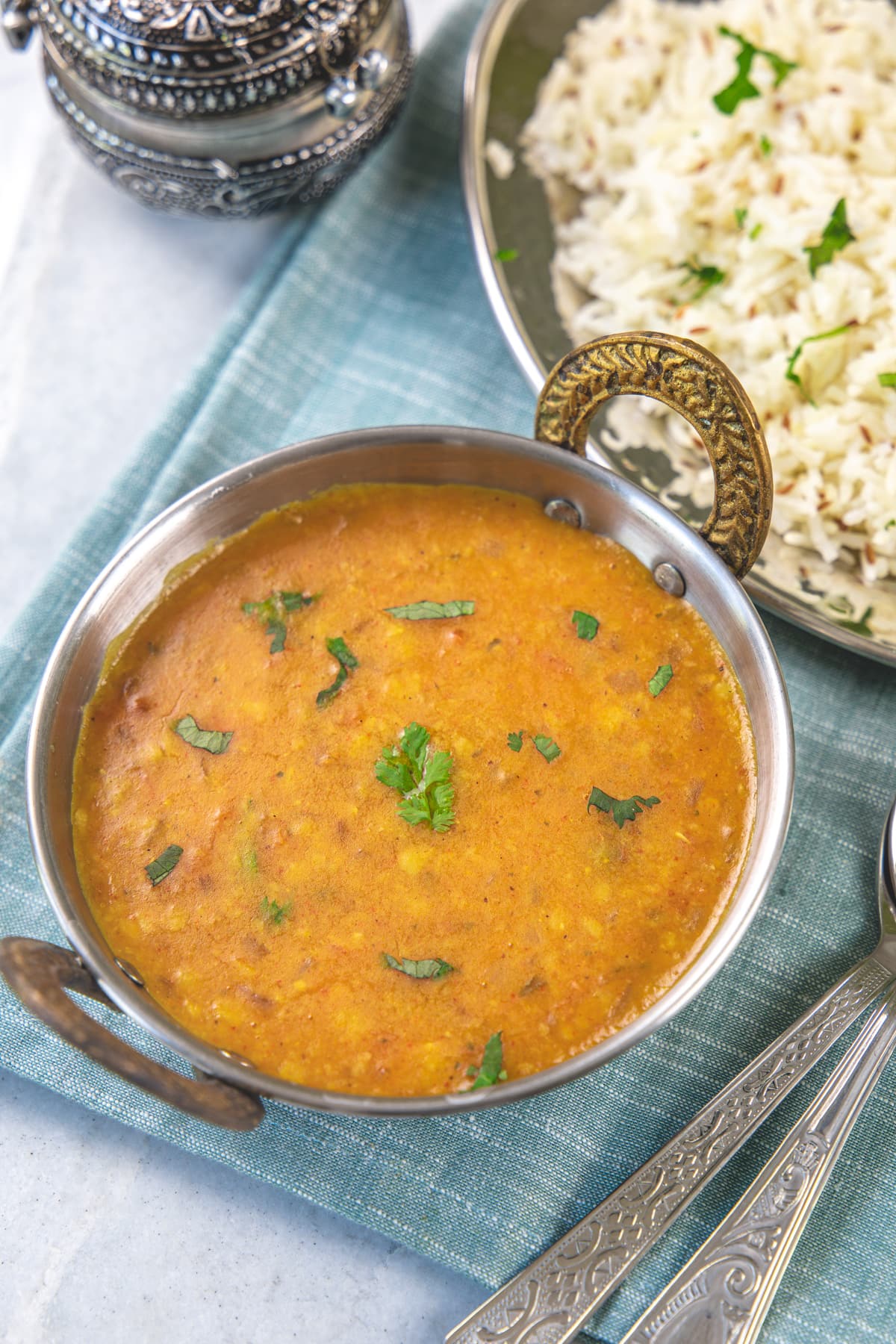 Dal fry in a serving kadai with rice on the side.