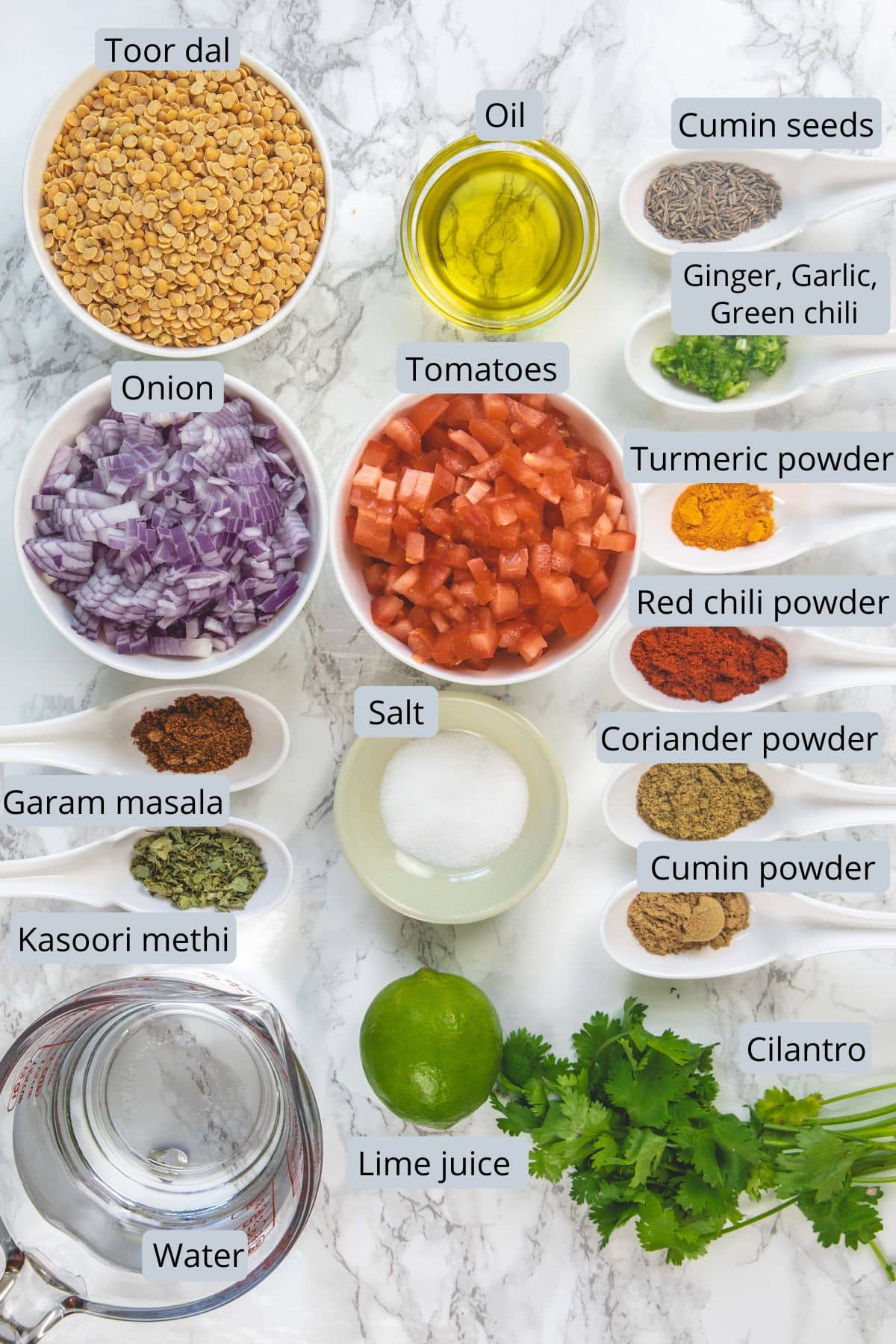 Dal fry ingredients in bowl and spoons with labels.