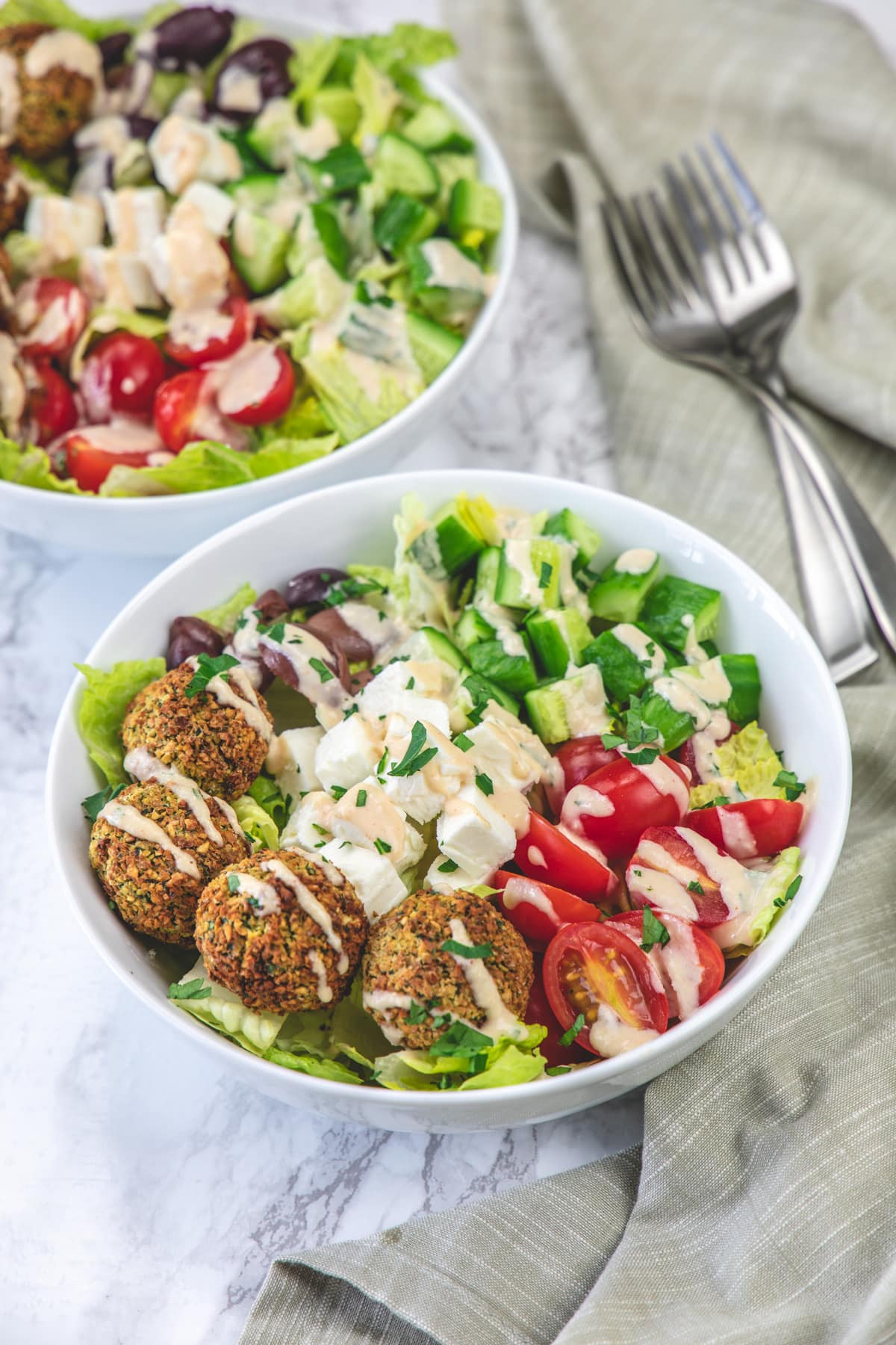 Falafel salab bowls with forks and napkin on the side.