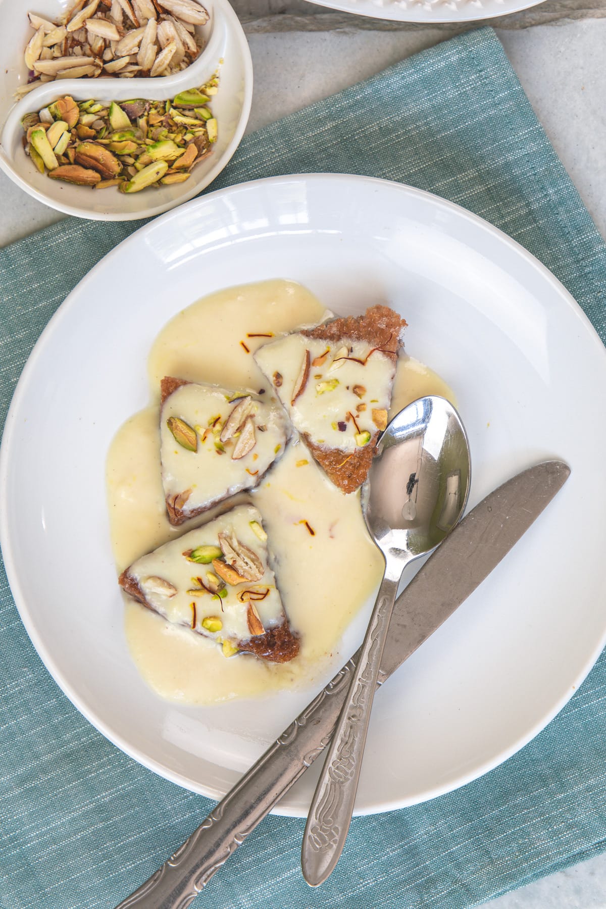 3 pieces of shahi tukda in a plate with knife and spoon.