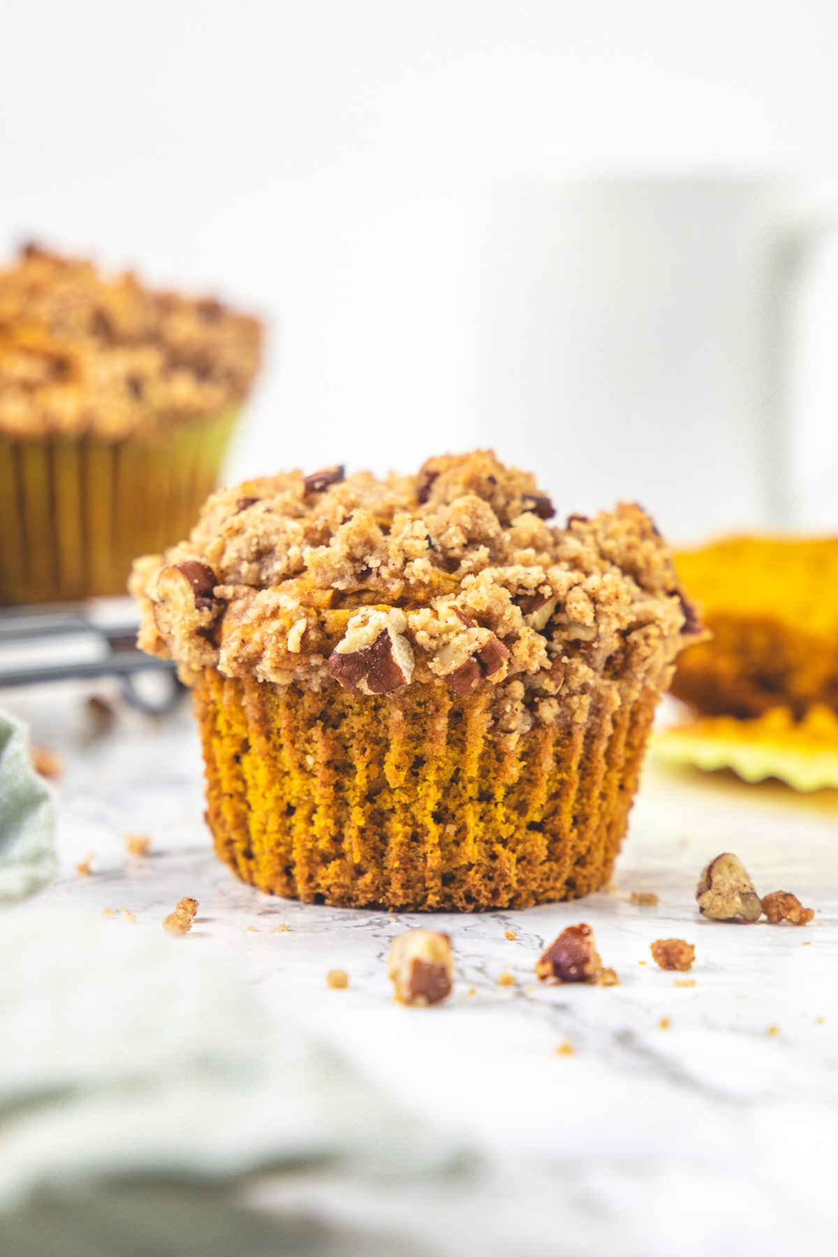 Eggless pumpkin muffin with few more muffins and a cup in the back.