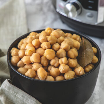 A bowl of cooked chickpeas with napkin on side and instant pot in the back.