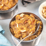 A bowl of moong dal halwa with spoon, 2 more bowls in the back.