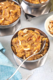 A bowl of moong dal halwa with spoon, 2 more bowls in the back.