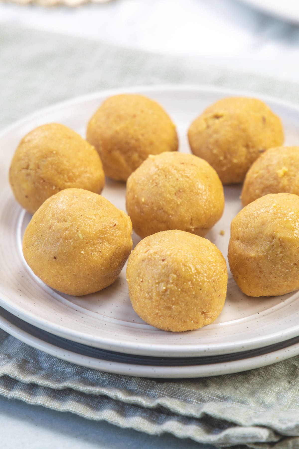 8 rava besan ladoo arranged on a plate with napkin underneath.