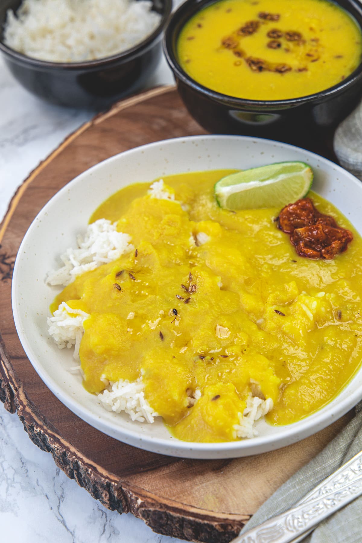 Varan bhaat with lime wedge and pickle on a wooden board.