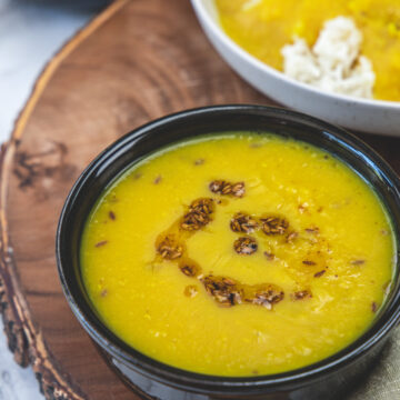 Varan in a black bowl with rice in another bowl and varan bhaat in a plate.