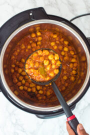 A ladleful of chana masala is taking from instant pot.