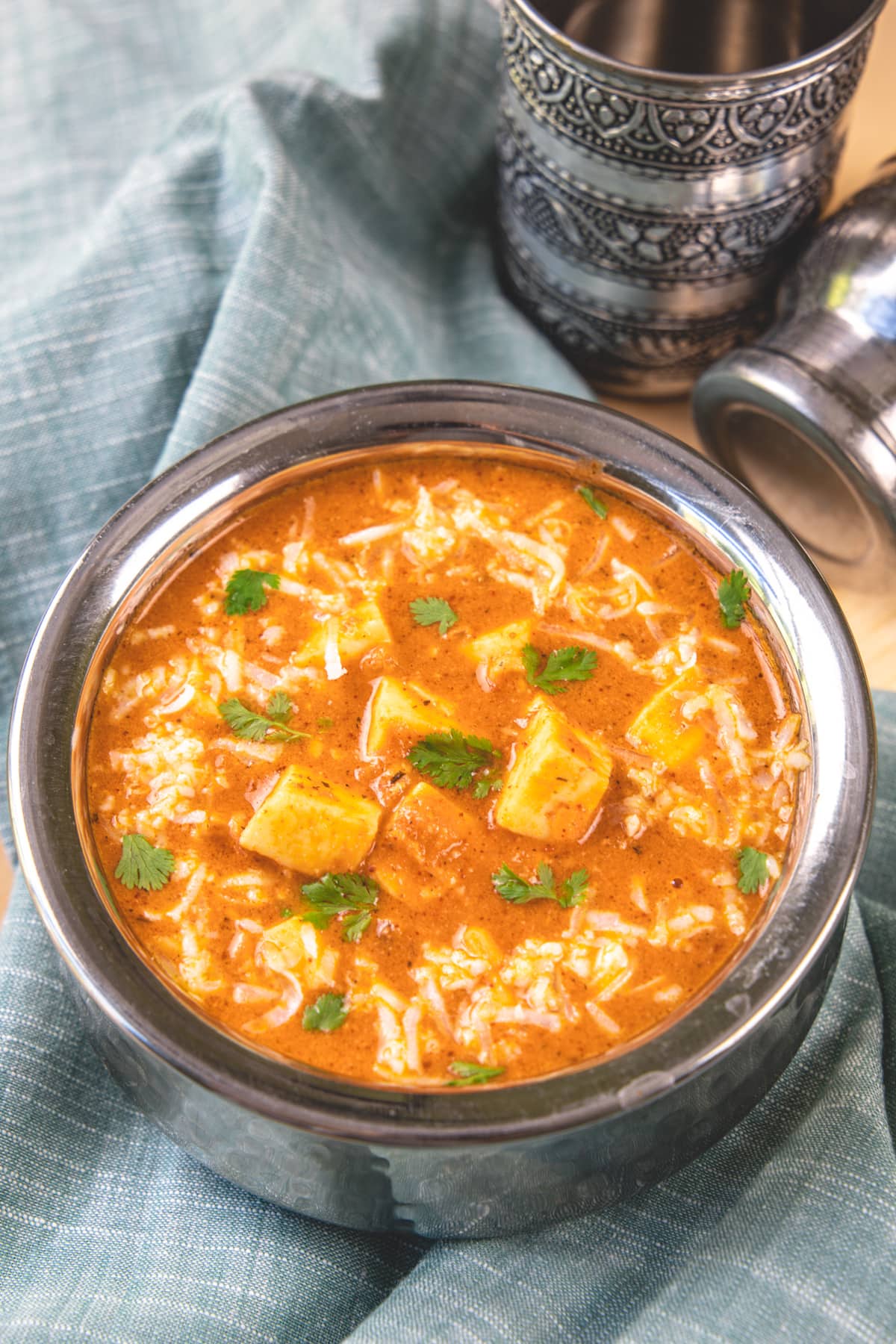 Paneer lababdar garnished with cilantro and a napkin under the serving bowl.