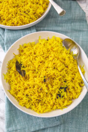 2 plates of turmeric rice with spoon in it.