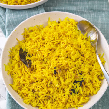 2 plates of turmeric rice with spoon in it.
