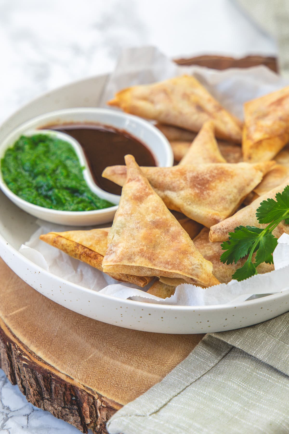 Cocktail samosa in a plate with 2 chutneys on the side.
