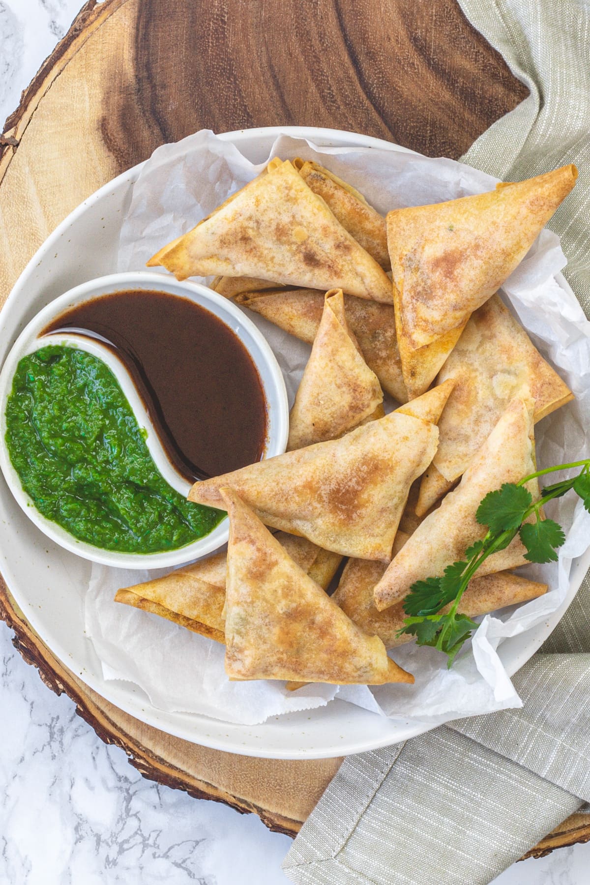 Paneer samosa in a plate with green chutney and tamarind date chutney.