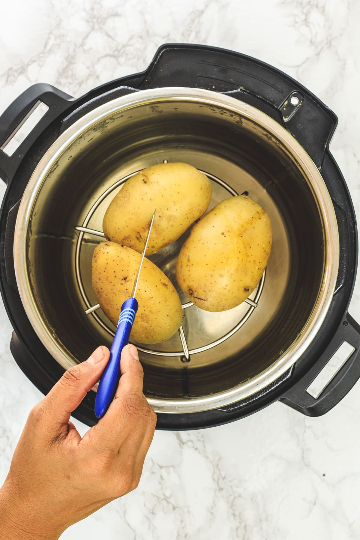 Boiled potatoes in instant pot and inserting a knife into a potato.