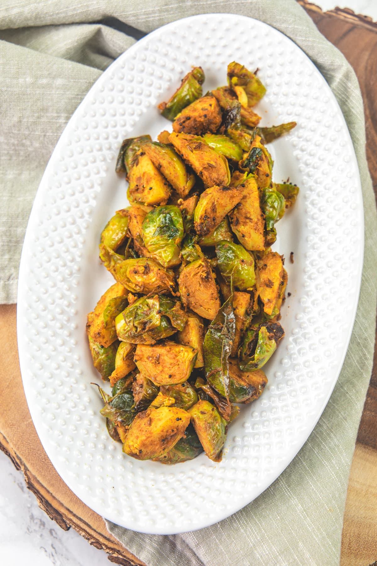 Brussels sprouts curry in an oval plate with a napkin under the plate.