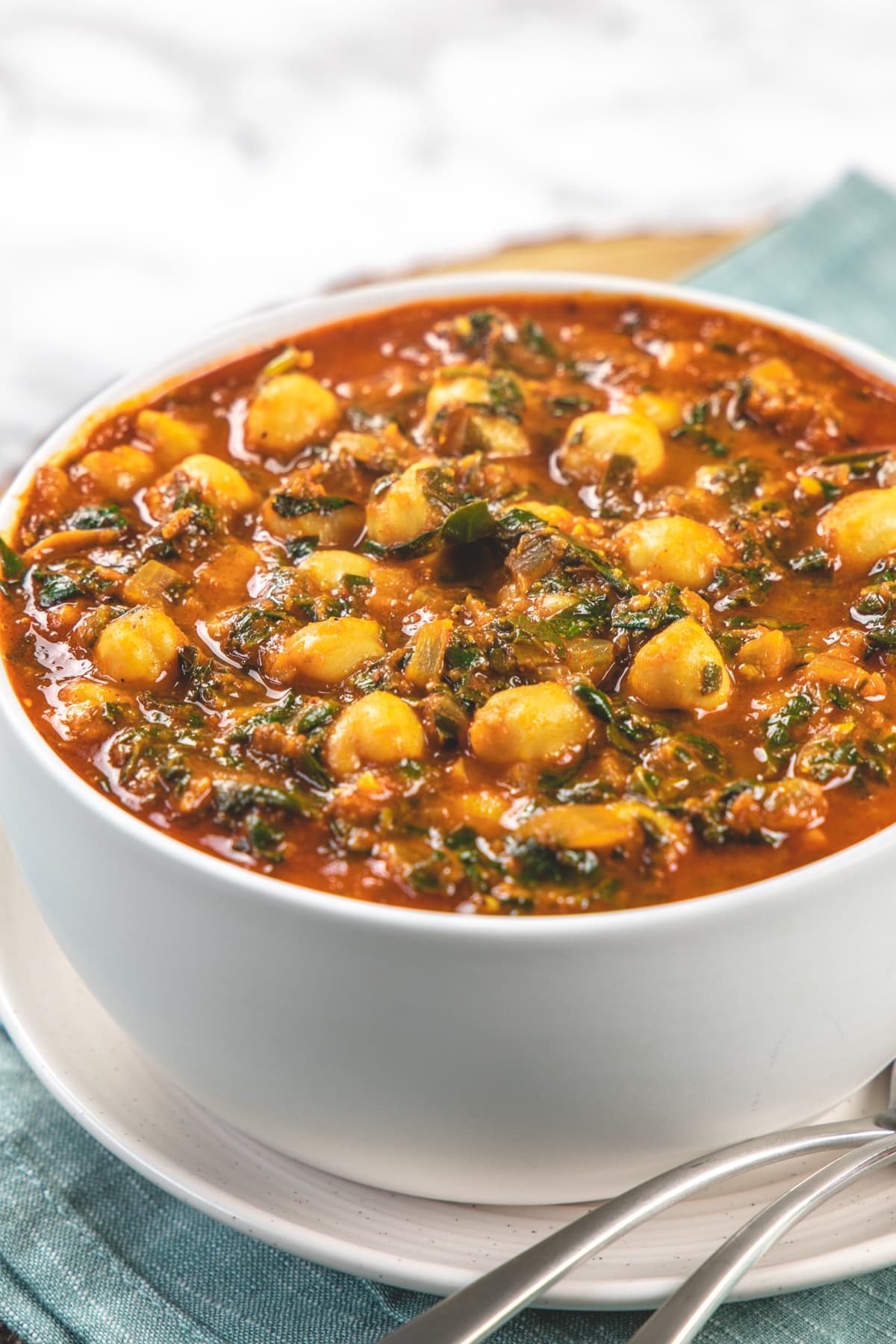 Chana saag bowl in a plate with 2 spoons in the plate.