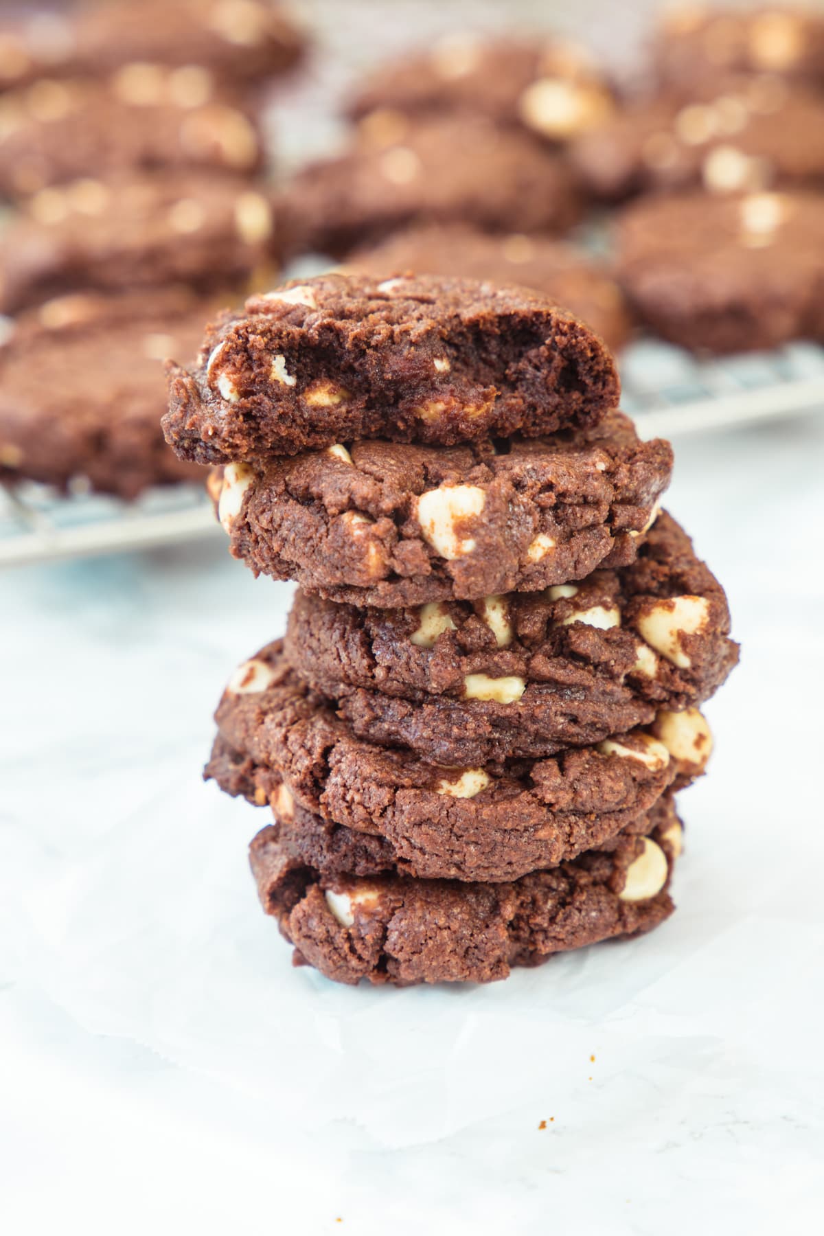 A stack of eggless chocolate cookies with top cookie has a bite taken.