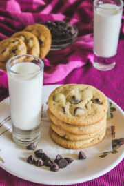 A stack of eggless chocolate chip cookies with a glass of milk.